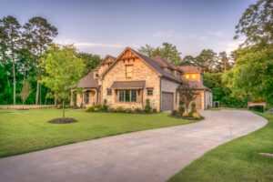 Elegant stone family home surrounded by trees, lush lawn, and vibrant garden.